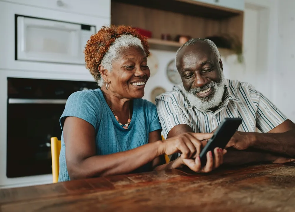 Two smiling seniors at their kitchen table with a free government phone